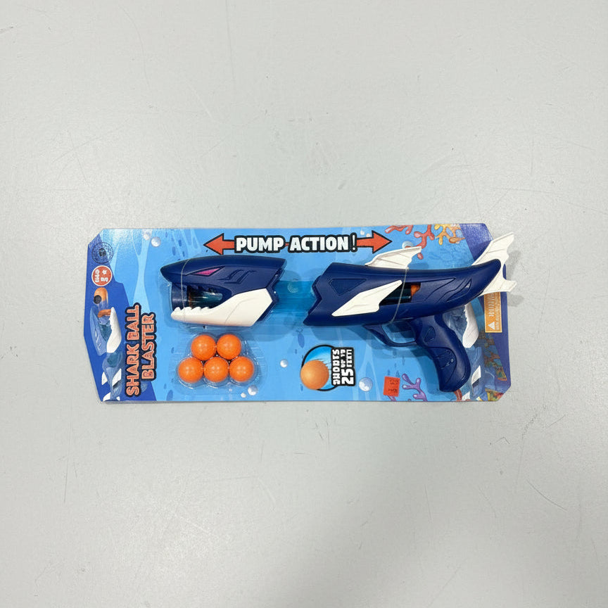 Toy packaging with a purple shark figure and orange balls on a gray concrete floor.