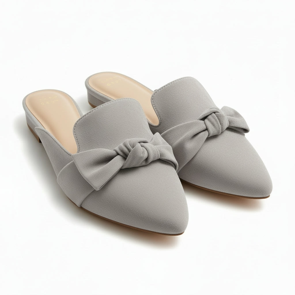 Pair of gray shoes with bow details on a beige surface