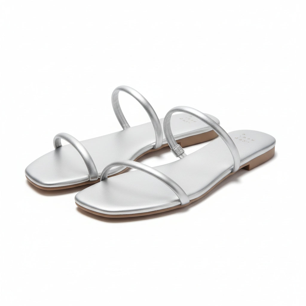Pair of silver sandals with a size tag on a brown surface