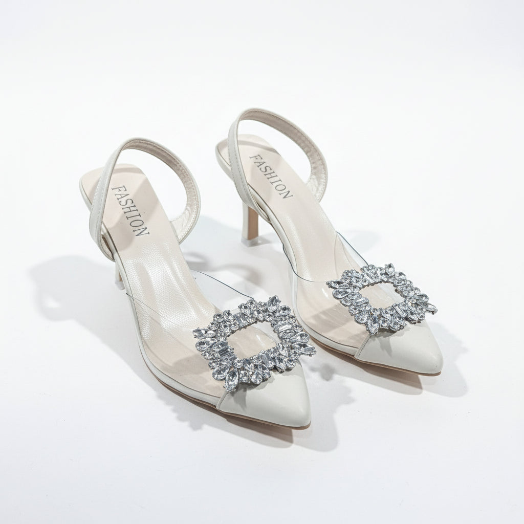 White high-heeled shoes with decorative straps on a cardboard surface