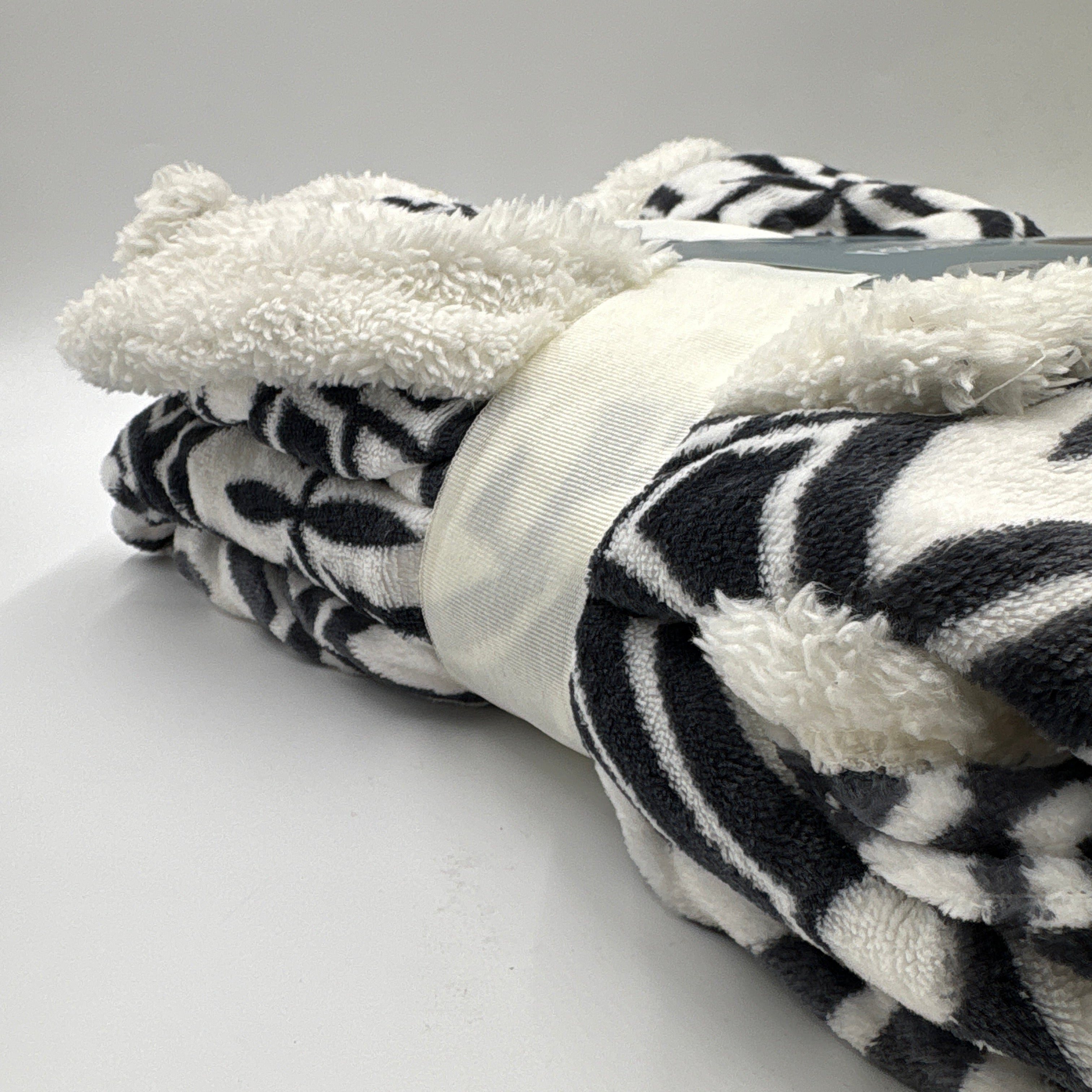 Black and white patterned headband with fluffy white ends on a mannequin head.