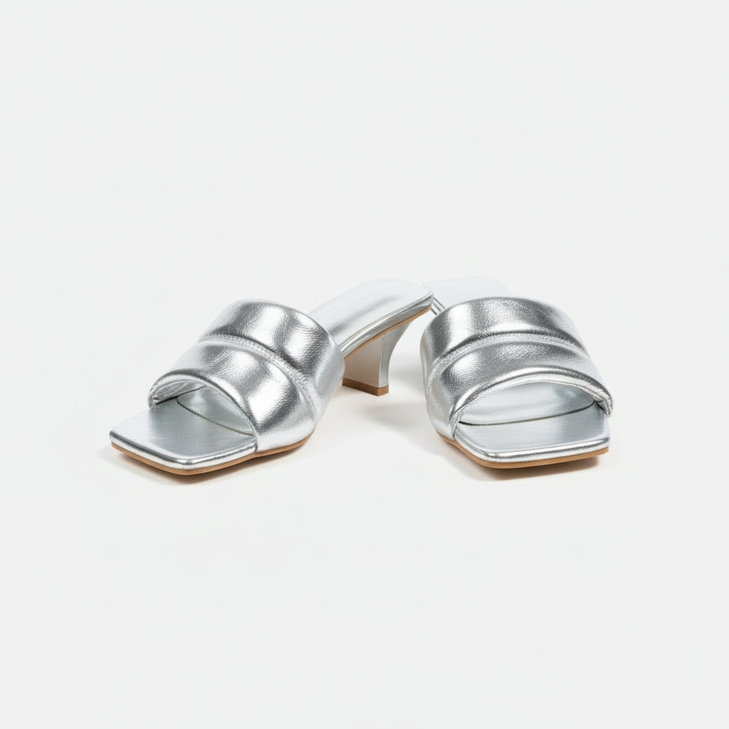 Silver high-heeled shoes on a cardboard box