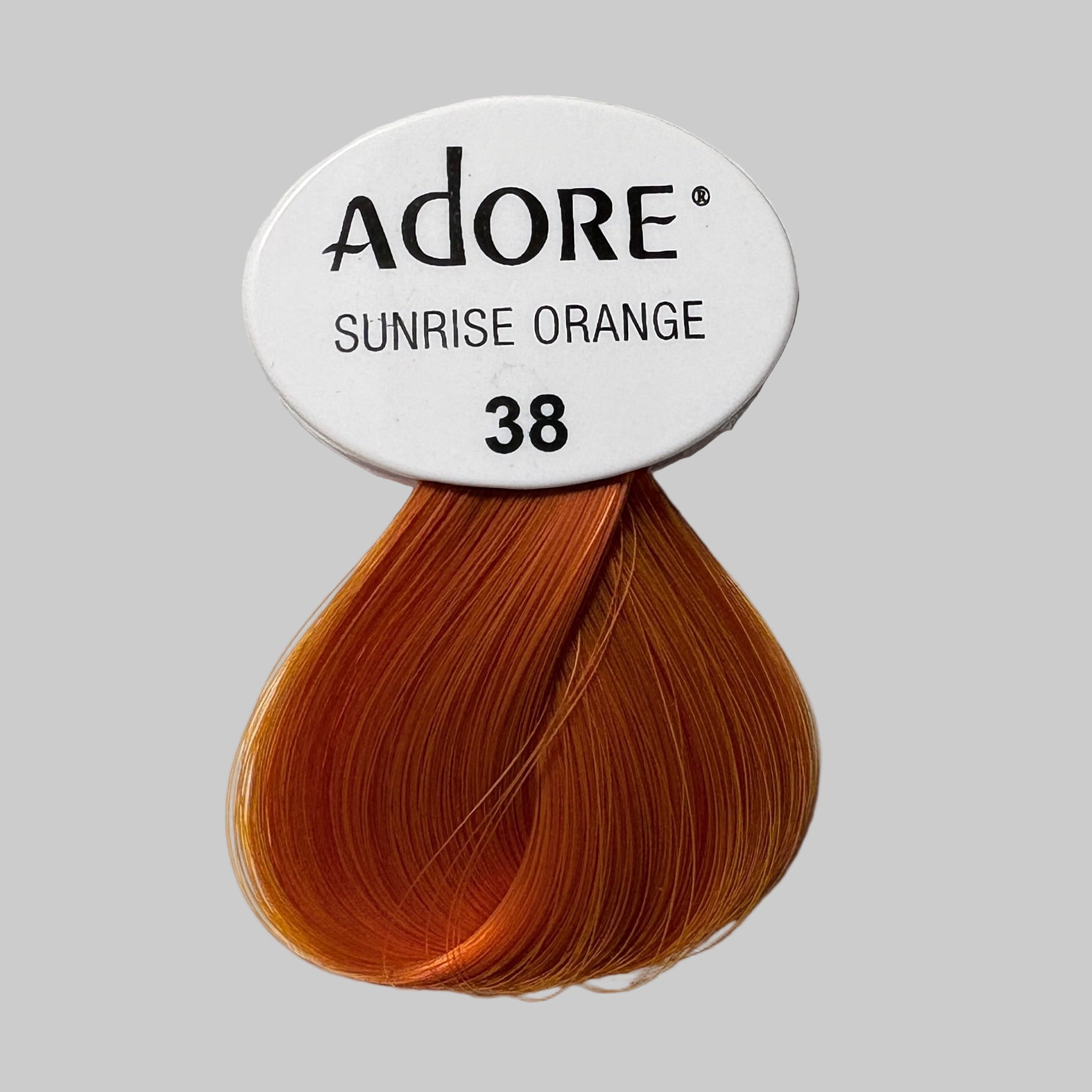Adore hair color packaging with 'Sunrise Orange' shade on a shelf.