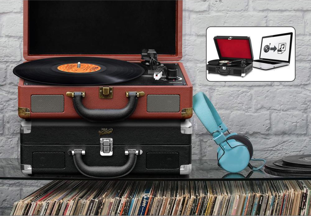 Record player in a suitcase with headphones and vinyl records on a gray brick wall background