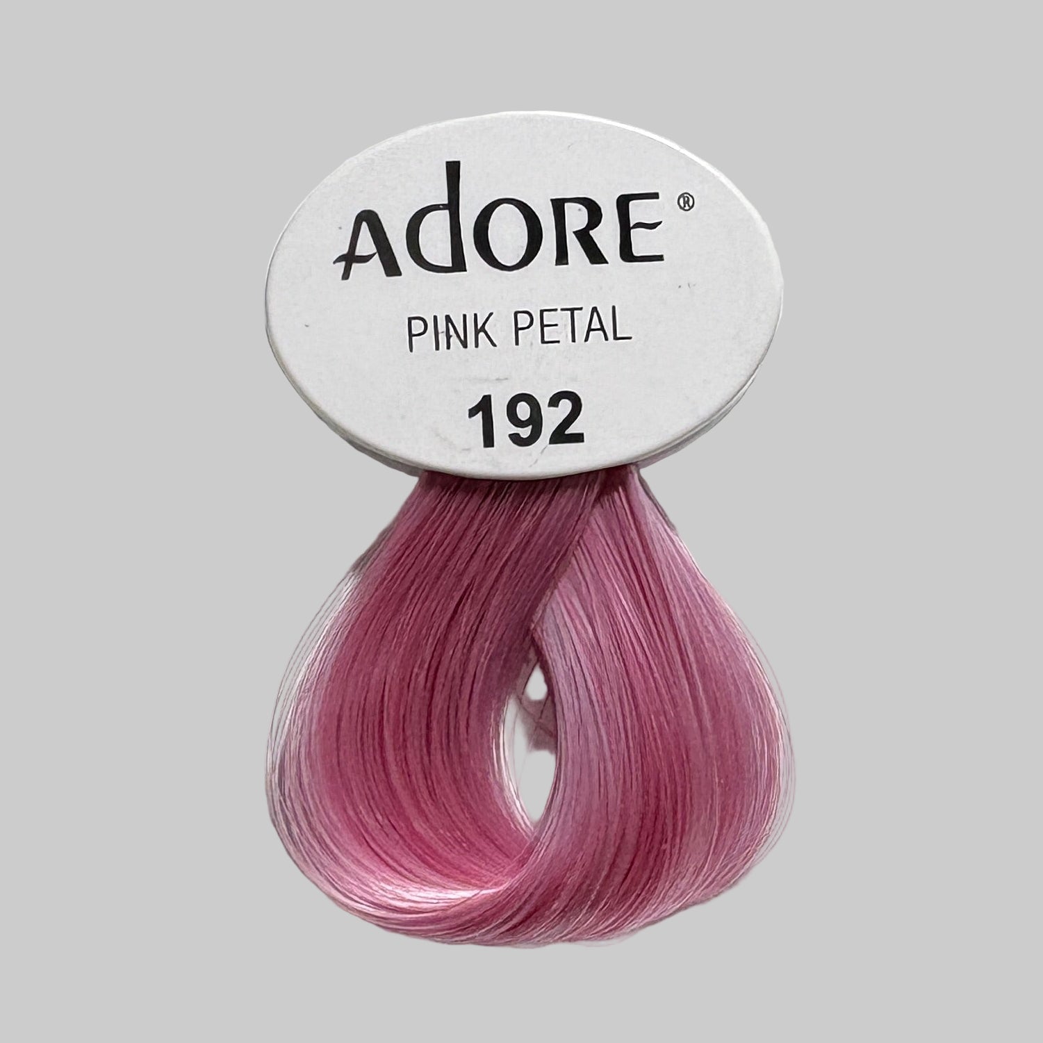 Display of Adore hair color products with pink petal shade on a shelf.