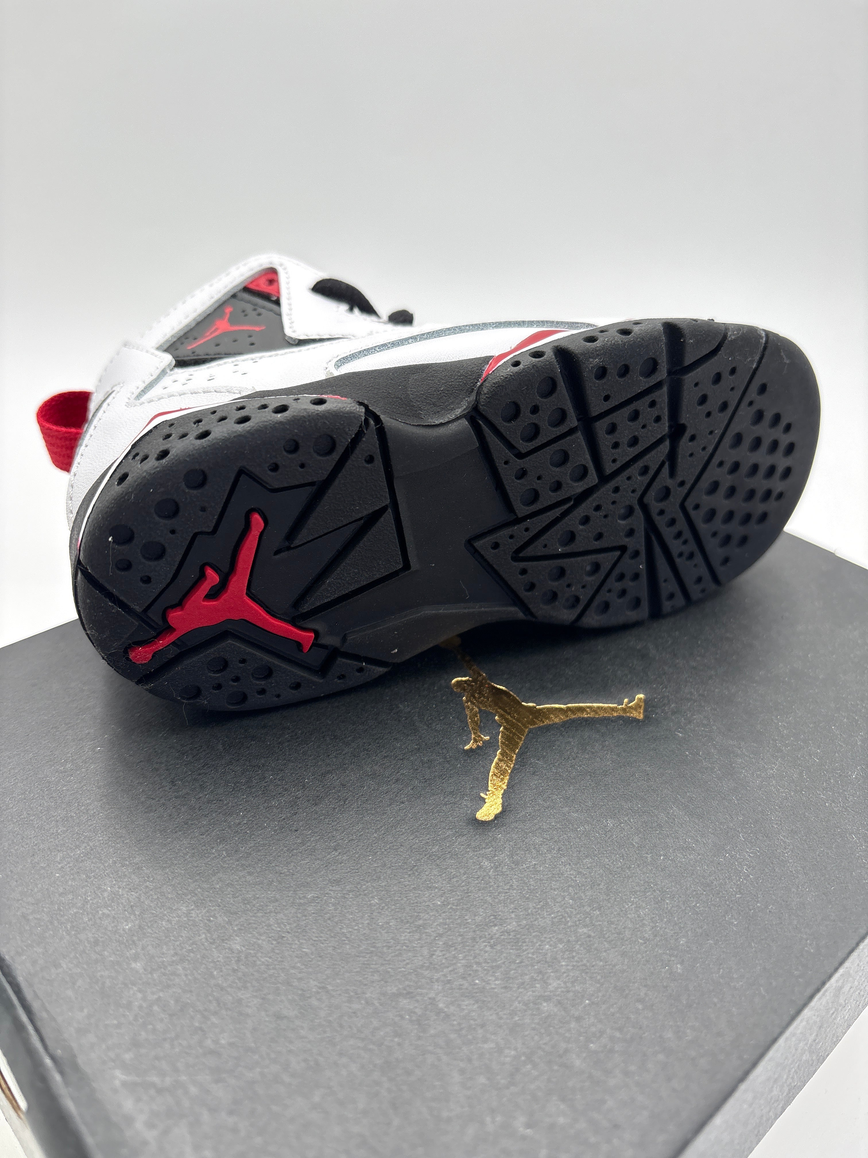 Jordan True Flight toddler shoes with black and red sole on black box featuring gold Jumpman logo