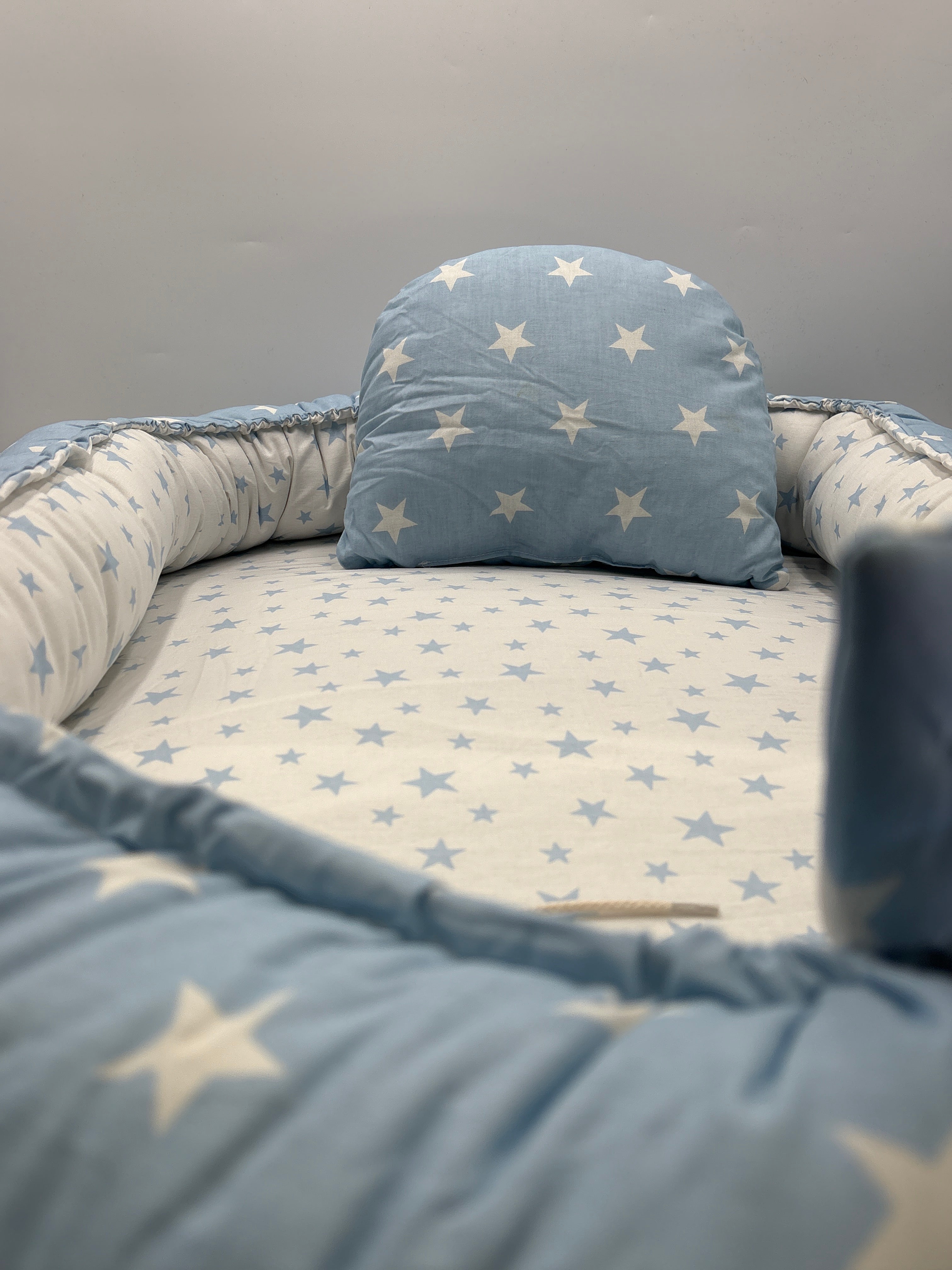 Blue portable baby lounger with washable cover featuring white star patterns and cushioned edges