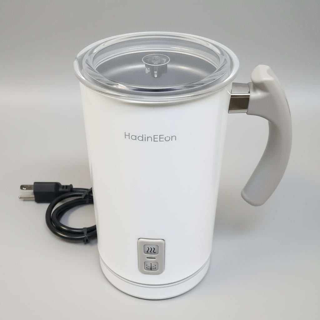 White electric milk frother with a clear lid on a white surface
